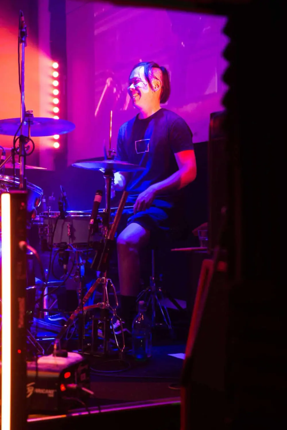 Nate behind the drum kit under magenta lighting